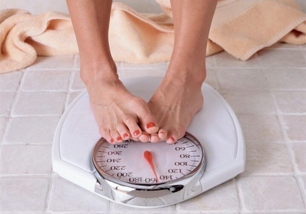 A person standing on a scale in front of a towel.